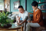 Senior Asian couple checking blood pressure at home. Wife examining blood pressure on her husband's arm with a blood pressure monitor. Elderly and healthcare concept