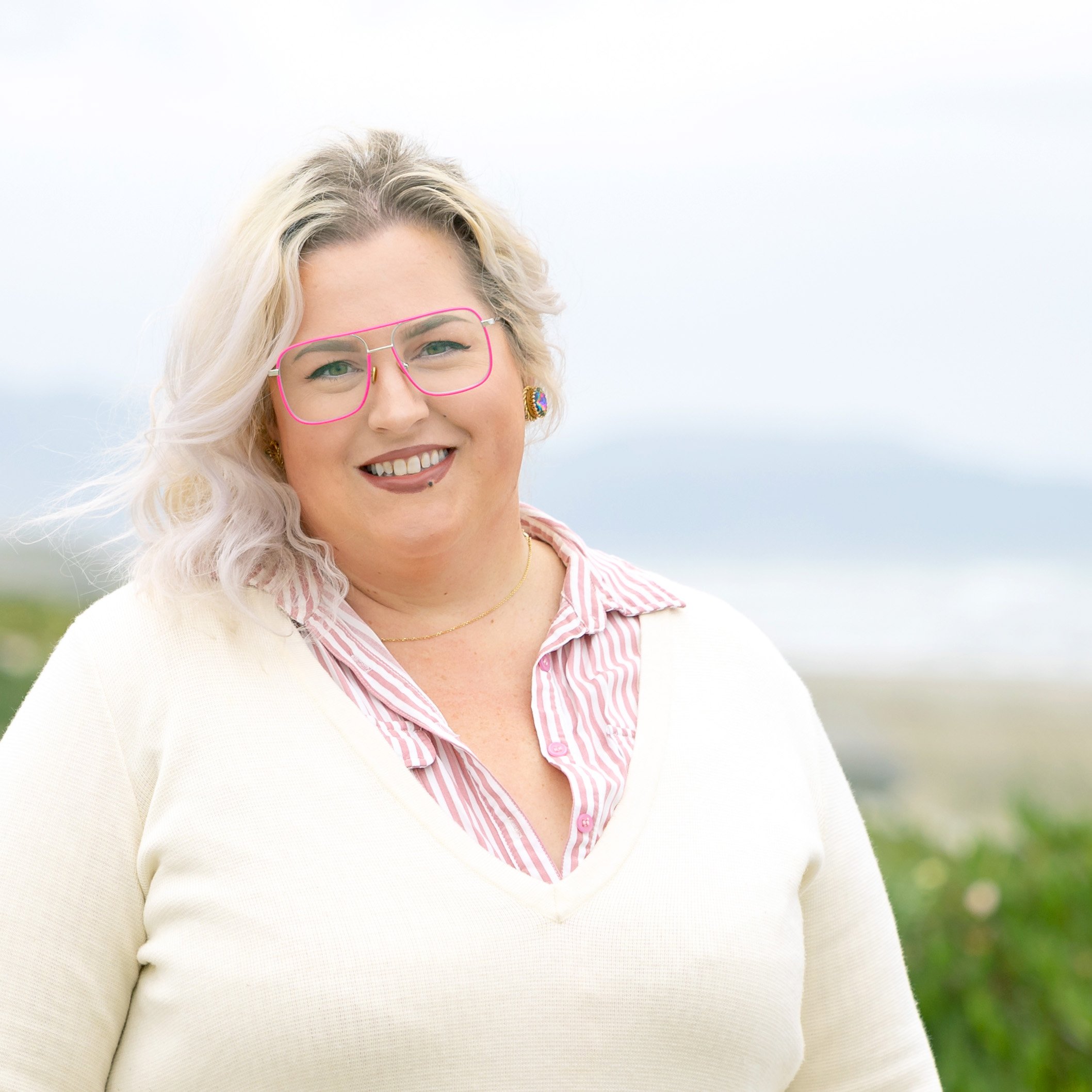 Tracy, a stroke survivor and Kandu program participant, smiling outdoors and wearing pink glasses.