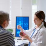 Doctor explaining to a stroke survivor how different regions of the brain are affected by a stroke using a human brain model.